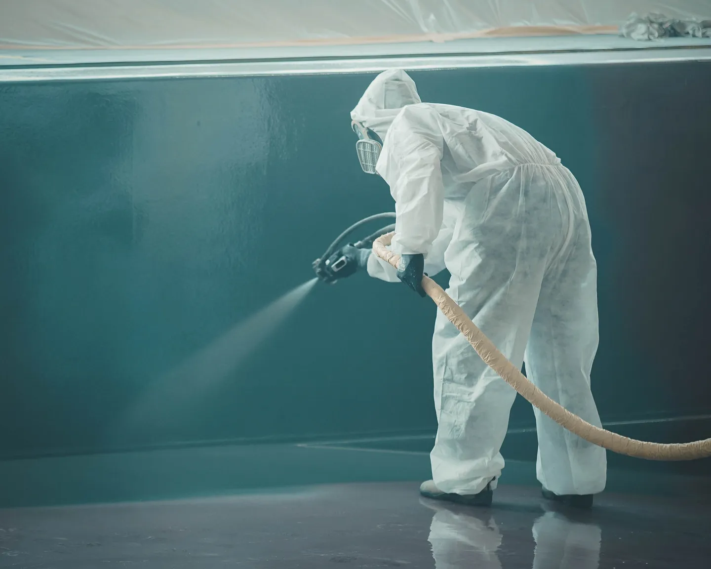 A person in white suit spraying water on the floor.