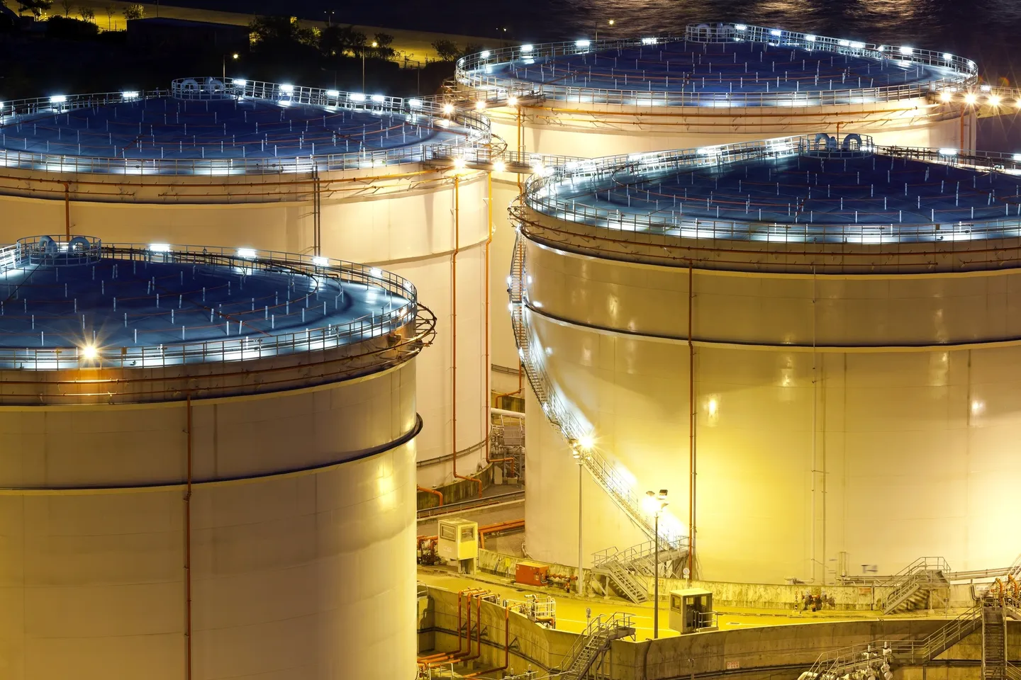 A group of large white tanks with lights on them.